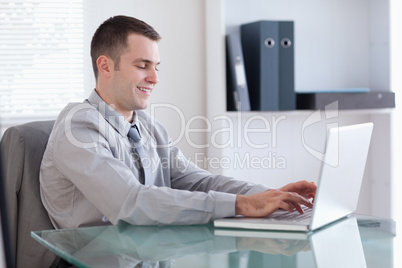 Smiling businessman working on his laptop