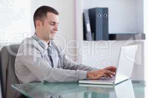 Smiling businessman working on his laptop