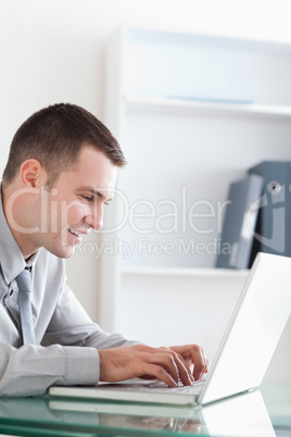 Smiling businessman typing on his notebook