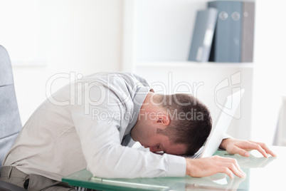 Overworked businessman taking a nap on his laptop