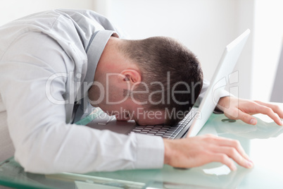 Close up of overworked businessman taking a nap on his laptop