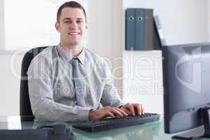 Smiling businessman typing on his computer