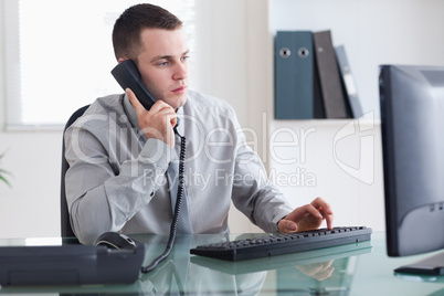 Businessman listening to caller while typing