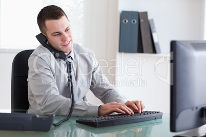 Businessman on the telephone and typing on his computer Businessman on the telephone and typing on his computer