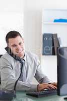 Businessman talking on the phone while using his computer