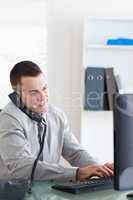 Businessman using his computer while talking on the phone