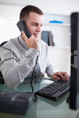 Businessman talking to costumer on the phone while using his com