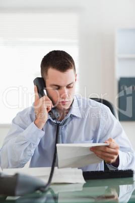 Close up of businessman looking at a letter while on the phone