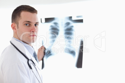 Serious looking doctor holding x-ray against light