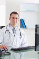 Smiling doctor sitting on his computer