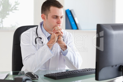 Thinking doctor looking at his screen