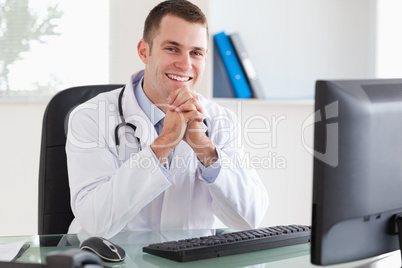 Smiling doctor sitting at his desk