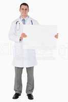 Standing doctor holding a sign to his left
