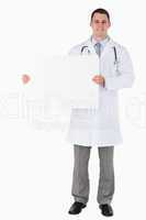 Standing doctor holding a sign to his right