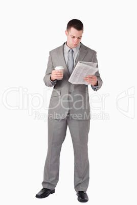 Portrait of a businessman reading the news while holding a cup o