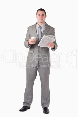 Portrait of a businessman holding a newspaper and a cup of coffe