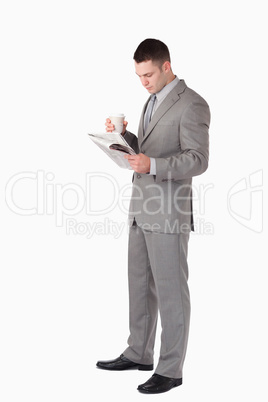 Portrait of a businessman holding a cup of tea while reading the