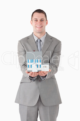 Portrait of a businessman showing a miniature house