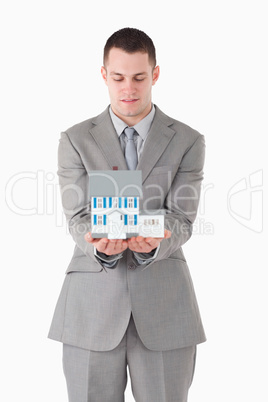 Portrait of a businessman looking at a miniature house