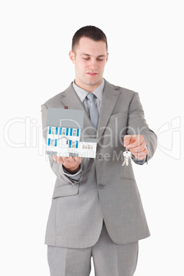 Portrait of a businessman showing a miniature house and keys