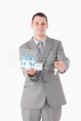 Portrait of a smiling businessman showing a miniature house and