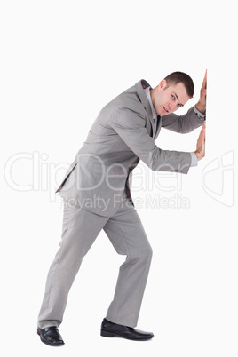 Portrait of a young businessman pushing a wall