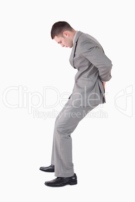 Portrait of a young businessman pushing a wall with his back