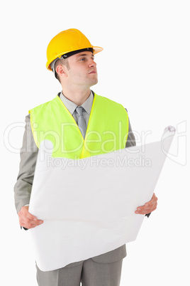 Portrait of a young builder looking around while holding a plan