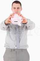 Portrait of a businessman shaking a piggy bank