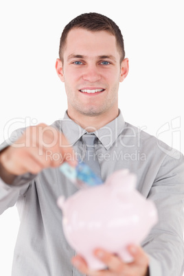 Portrait of a young businessman putting a twenty euros note in a