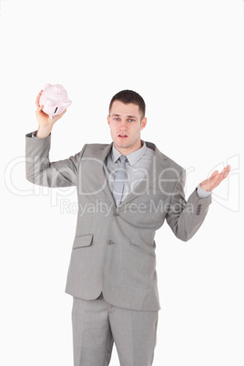 Portrait of a broke businessman shaking an empty piggy bank