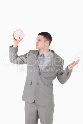 Portrait of a broke businessman looking at an empty piggy bank