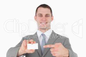 Smiling businessman pointing at a blank business card