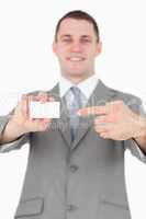 Portrait of a young businessman pointing at a blank business car