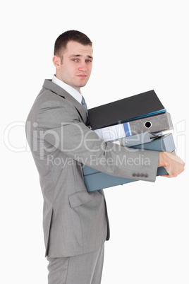 Portrait of a stressed businessman holding a stack of binders