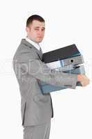 Portrait of a stressed businessman holding a stack of binders