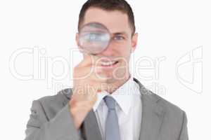 Young businessman looking through a magnifying glass
