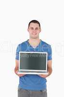 Portrait of a young man holding a laptop