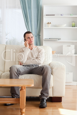 Portrait of a man on the phone while sitting on his sofa