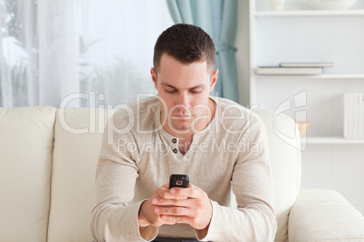 Man sending text messages while sitting on his couch
