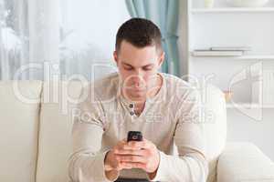 Man sending text messages while sitting on his couch