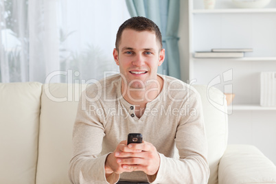 Man sending text messages while sitting on a sofa