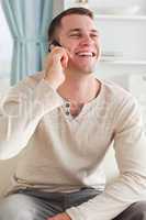 Portrait of a laughing man making a phone call while sitting on