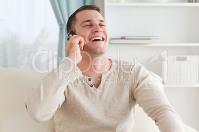 Laughing man making a phone call while sitting on a couch