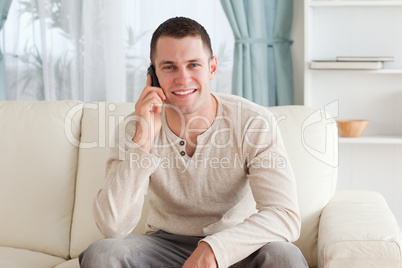 Handsome man making a phone call while sitting on a couch