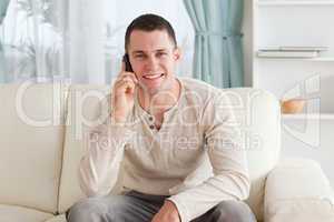 Handsome man making a phone call while sitting on a couch