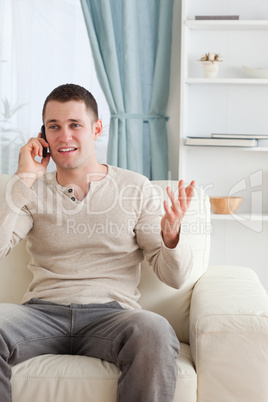 Portrait of a man talking through the phone while sitting on a c
