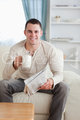 Portrait of a man holding a newspaper while drinking a tea