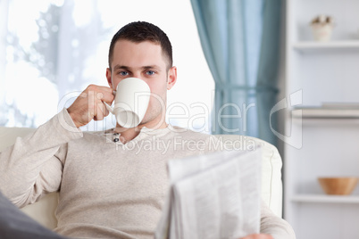 Handsome man having a tea while reading the news