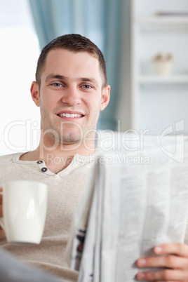 Portrait of a handsome man having a coffee while reading the new